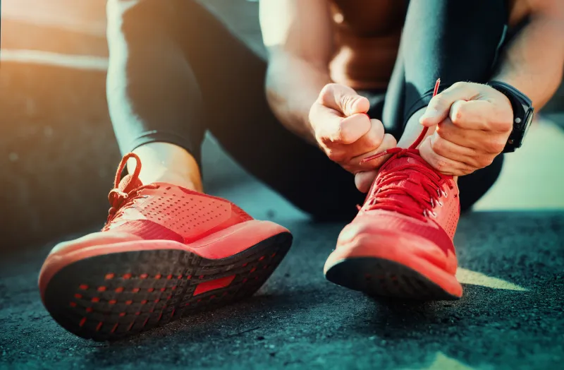 man tying jogging shoeshe is running outdoors on a sunny day