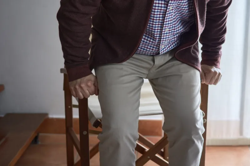 a mature man has difficulty getting up from an armchair in the l