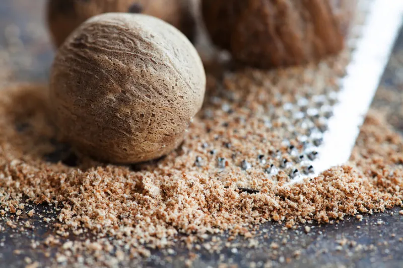 making nutmeg powder process nuts silver grater kitchen still life photo shallow depth of field, aged brown rusty background selective focus