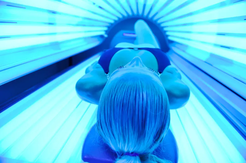 young woman at laying on solarium bed and get brown skin tone ready for summer