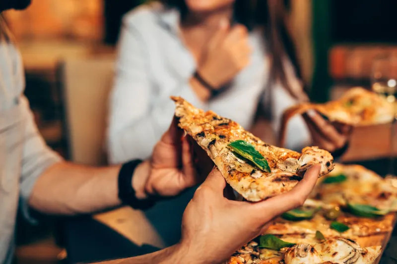 close up of people eating pizza