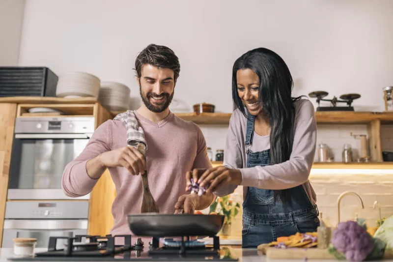 cute couple smiling and preparing lunch together in the kitchen at home