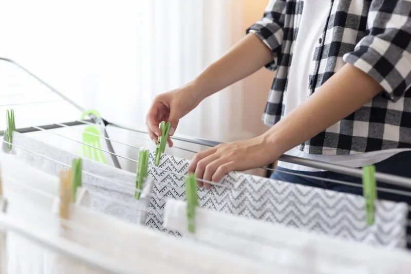 detail of female hands hanging the washing out to dry on a drying rack focus on the clothespin and the hand holding it