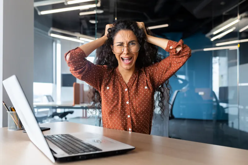 angry businesswoman yelling at camera, latin american woman holding her head angry working inside modern office using laptop at work