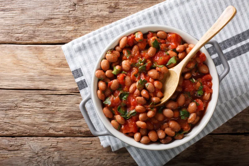 stewed cranberry beans or borlotti in tomato sauce with herbs close-up in a bowl on the table horizontal top view from above