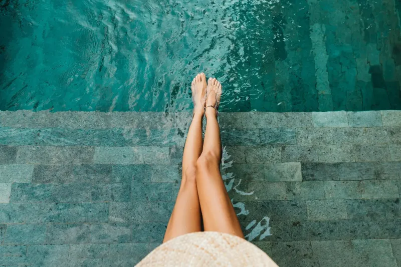 closeup of beautiful female legs in water of a pool summer concept