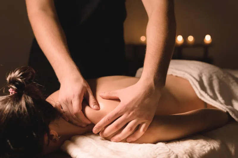 close up male manual worker doing spa massage to a young girl in a dark room