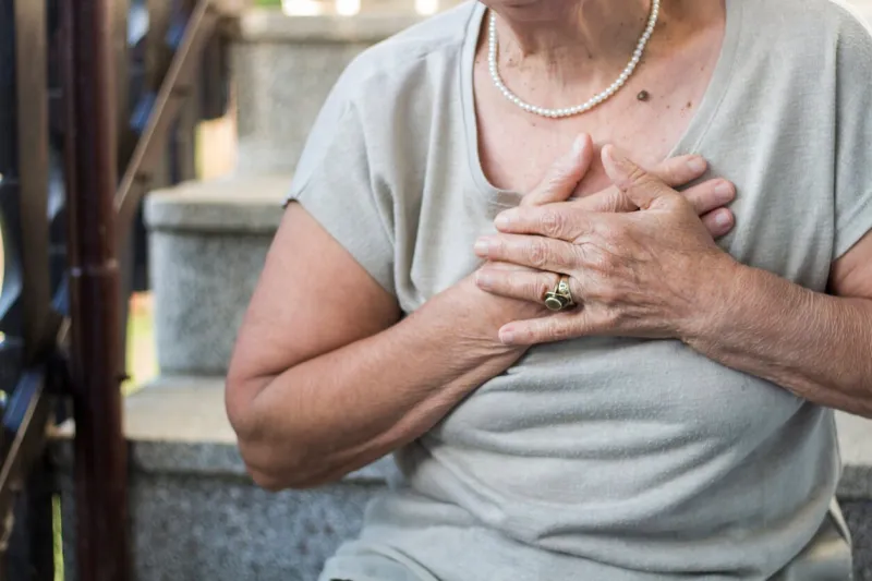 elderly woman sitting on stairs and holding hands on chest due to short breath upset stressed senior woman feeling pain ache touching chest having heart attack, sad worried senior older lady suffers from heartache