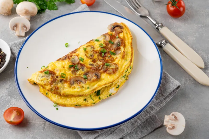 omelet with fried mushrooms and fresh herbs in a plate on a concrete background delicious healthy breakfast top view copy space