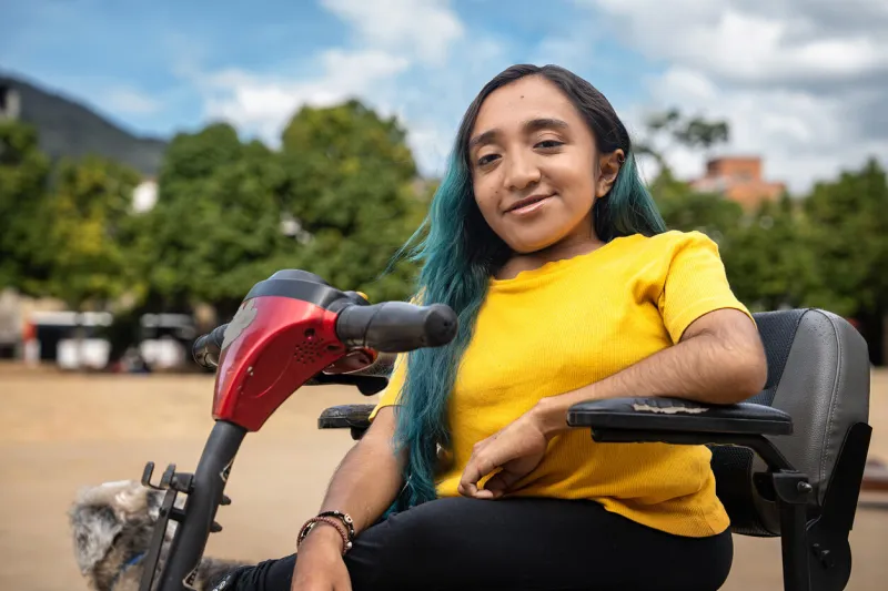 woman with osteogenesis imperfecta and dwarfism using an electric wheelchair in a public park