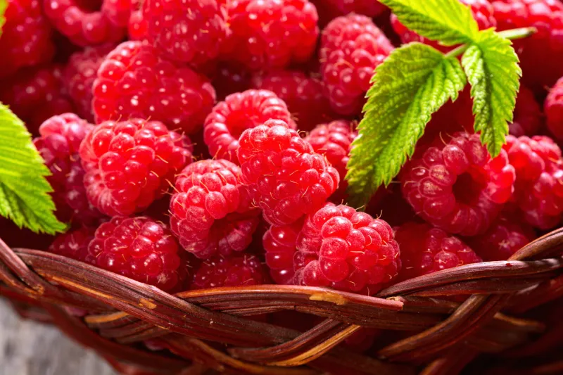 raspberry in a basket on wooden background top view