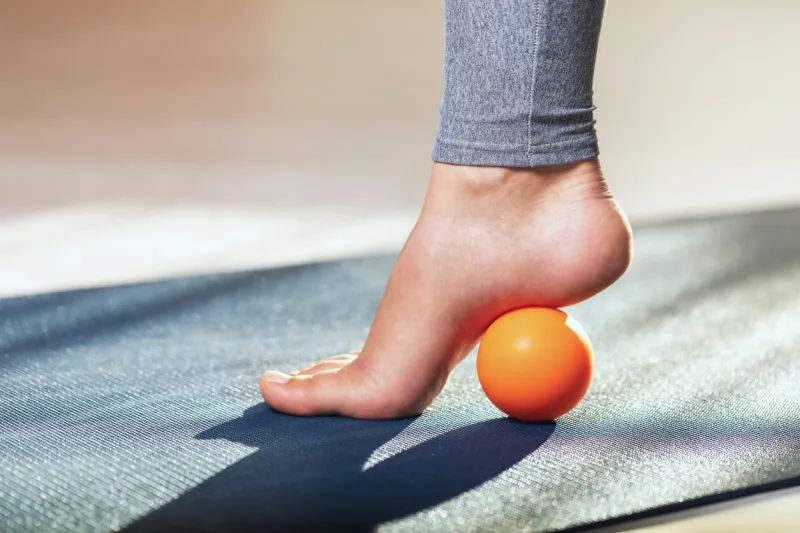 myofascial release of hyper-movable muscles of the foot with a massage ball on a gymnastic mat at home prevention of leg fatigue after wearing high heel shoes