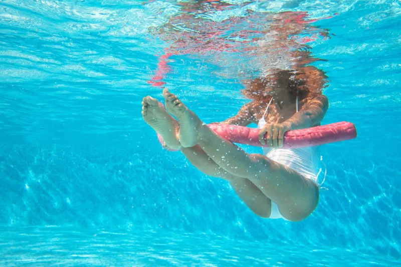 sporty woman doing water aerobics in a pool with a buoy