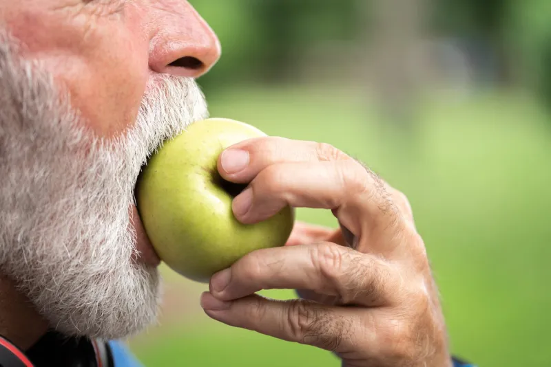 senior sportsman eating green apple