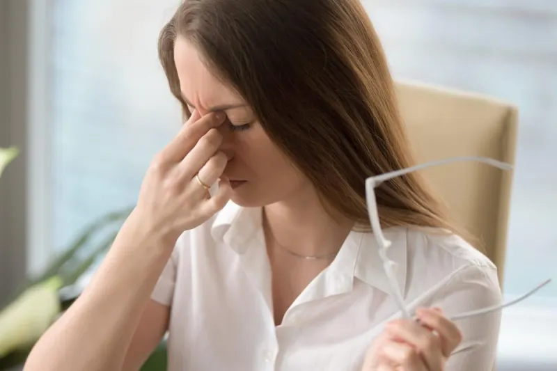 femme fatiguée massant le pont du nez tout en tenant des lunettes, se sentant fatigué les yeux, dame exténuée souffrant de maux de tête ou de migraine, malaise après une longue période de port de lunettes, problème de vue, coup de tête