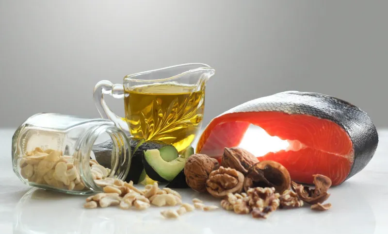 les acides gras oméga-3, y compris le steak de saumon, l'huile d'olive, l'avocat, les noix et les noix de cajou, debout sur le marbre blanc, comprennent un espace pour le texte