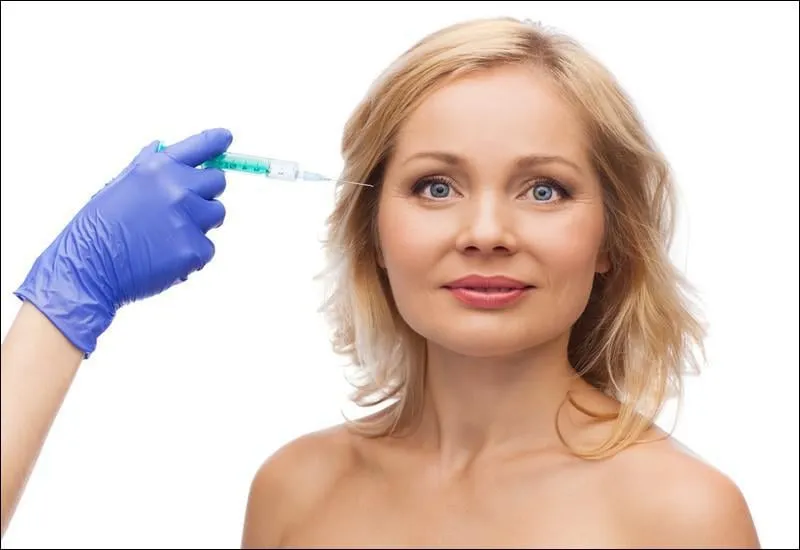 beauté, concept de chirurgie esthétique anti-âge - visage de femme souriante et esthéticienne main dans la main avec injection de seringue dans le contour de l'oeil