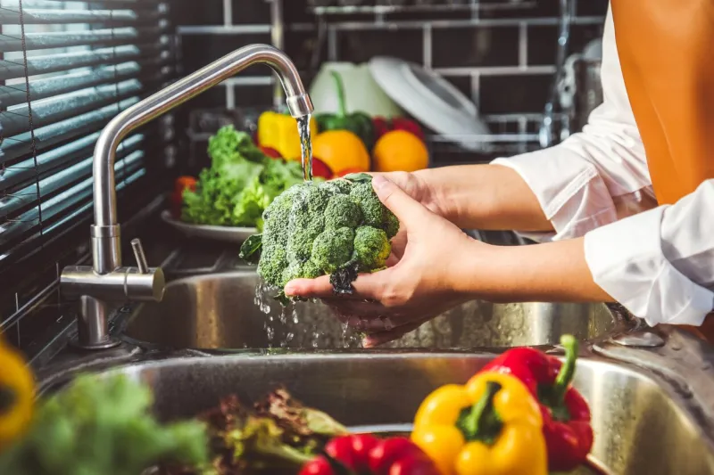 hand of maid washing tomato fresh vegetables preparation healthy food in kitchen