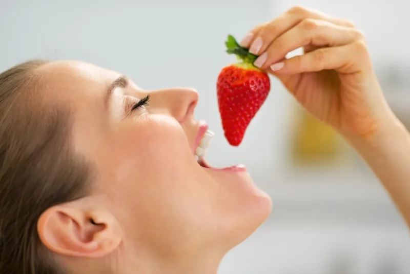portrait de jeune femme mangeant des fraises