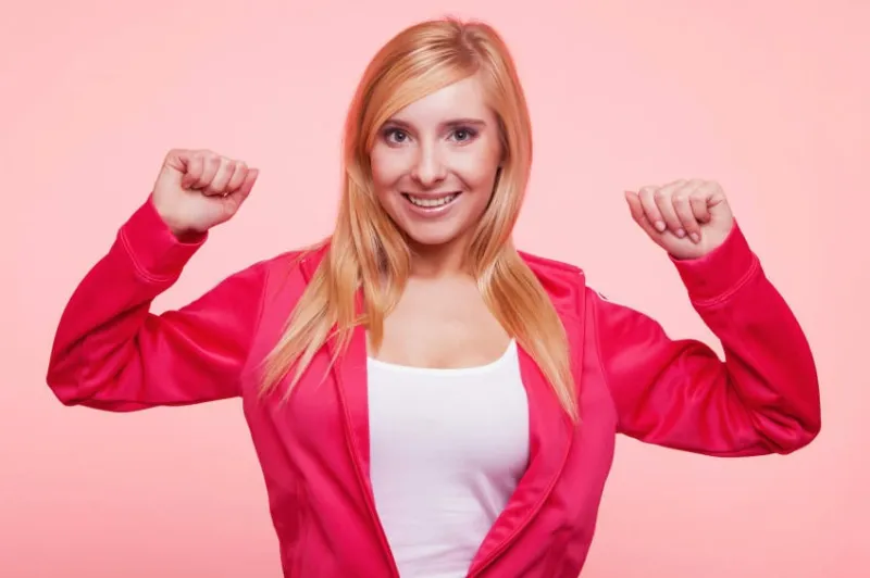 femme de remise en forme montrant l'énergie fraîche flexion biceps muscles sourire heureux sur fond rose fille dans sportswear énergique et amusant