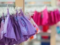se dresse avec des vêtements dans le centre commercial pour enfants