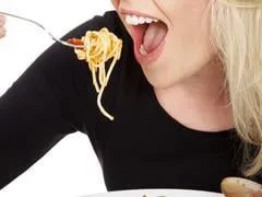 jeune femme blonde mange des spaghettis bouchent