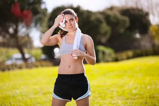 femme rafraîchissante après avoir couru au parc de la ville