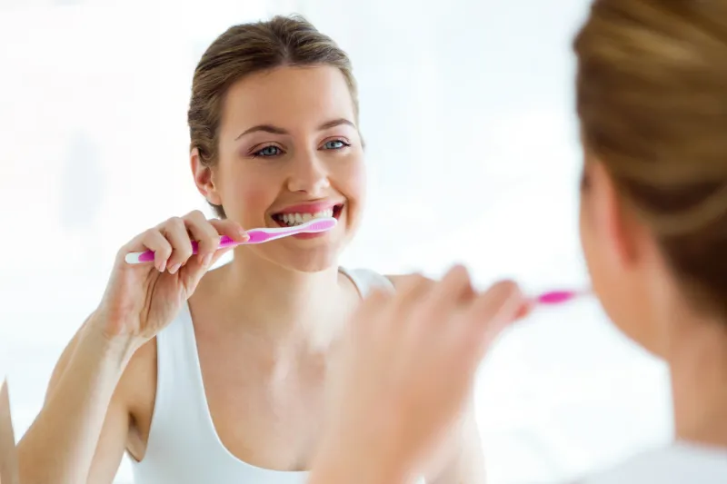 portrait of pretty young woman brushing her teeth in the bathroom at home