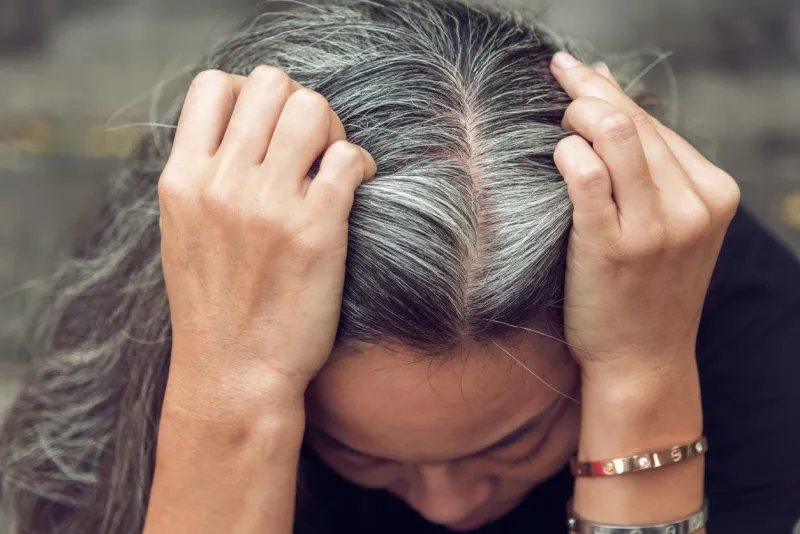 closeup sad asian young beautiful woman and gray hair with worried stressed face expression looking down