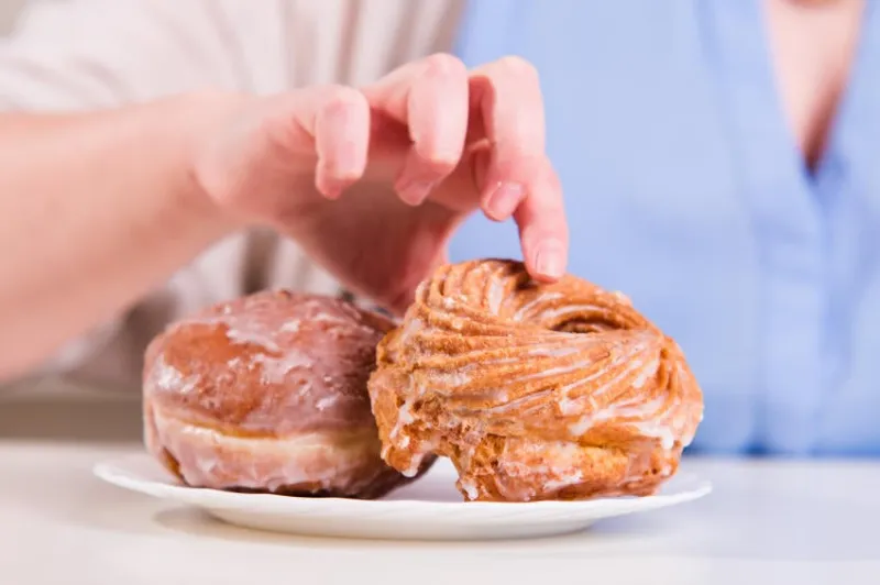 main atteint pour les beignets sucrés sur la table dans la cuisine