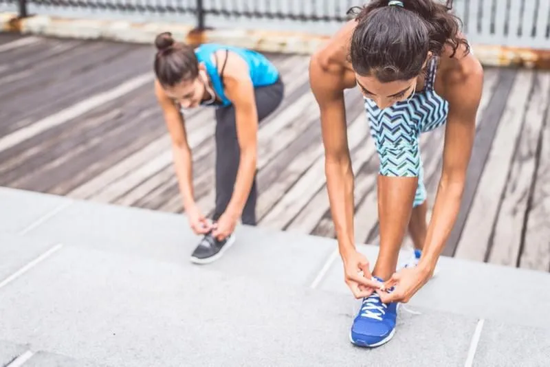 deux femmes sportives attachant lacets - les filles commencent une séance d'entraînement en plein air, copie espace sur la gauche