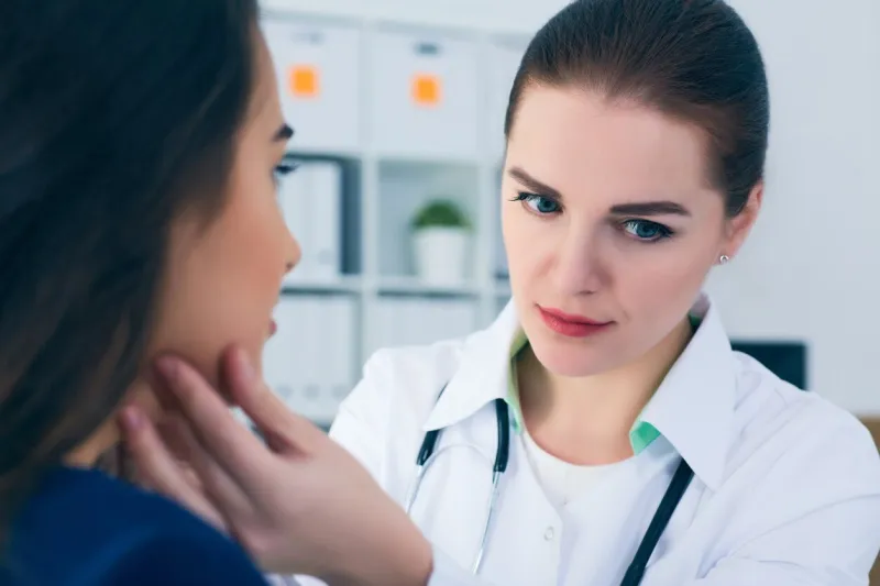 young female doctor palpating lymph nodes of a patient doctor touching the throat of a patient medical exam, clinic, hospital