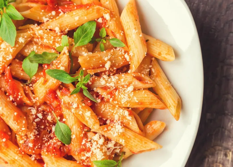 pâtes penne à la sauce tomate avec basilic et parmesan sur fond en bois rustique