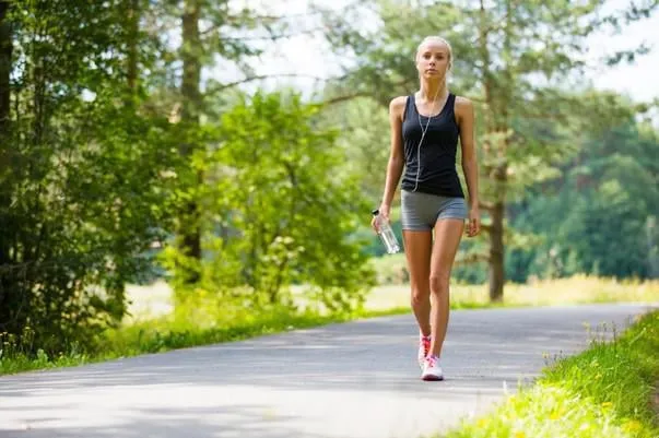 belle jeune femme blonde en forme et marcher sur la piste dans les bois d'entraînement en plein air