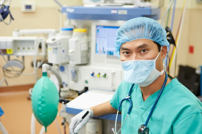 anesthetist working in operating theatre looking at camera