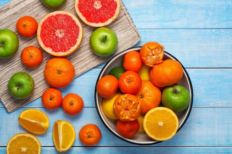 fond de saine alimentation sur une table en bois bleue dans un bol - pamplemousse, oranges, mandarines et pommes vue de dessus avec espace copie