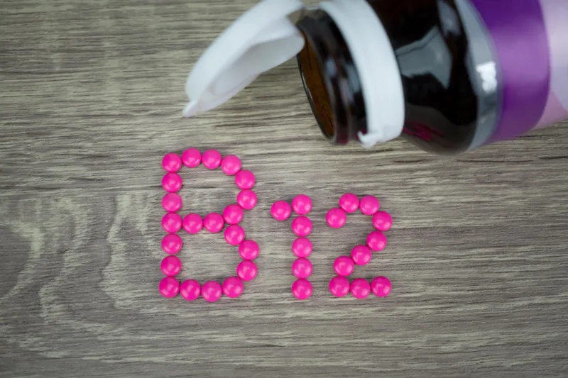 pilules roses formant la forme à l'alphabet b12 sur fond de bois