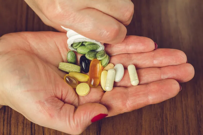 woman's hands poured the mix of vitamins and nutritional, dietary supplement pills from a bottle, close-up