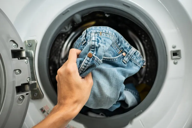 putting jeans into the washing machine