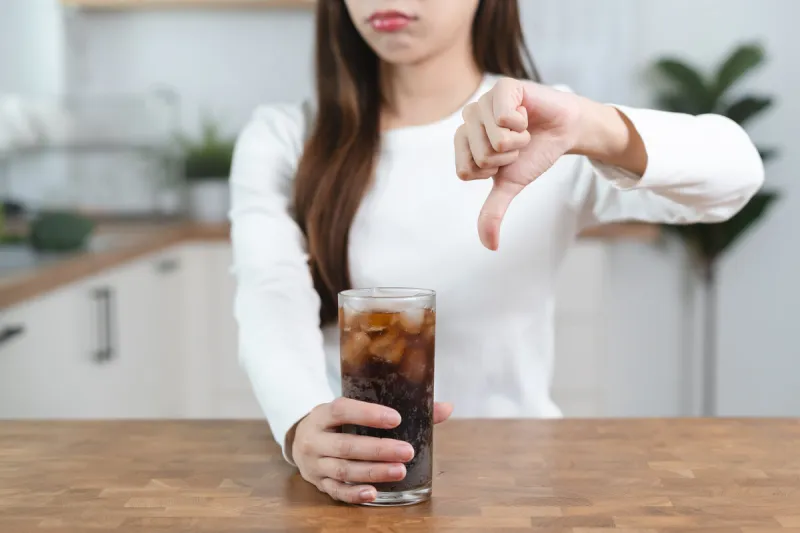 limits sugar diet in food concepts young woman showing bad hand symbol to soft drink soda that have high sugar
