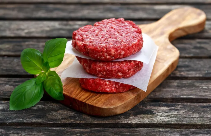 hamburgers de bœuf haché à la main maison sur planche à découper vieille table en bois