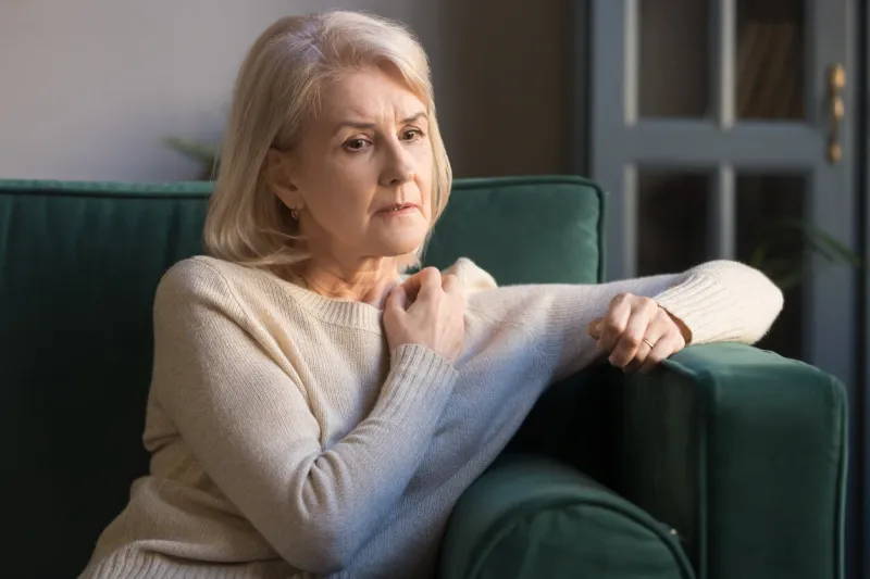 elderly grey-haired pensive depressed woman sit on sofa alone at home lost on sad thoughts, grandmother thinking about problems difficulties, having senile diseases, mental emotional disorders concept