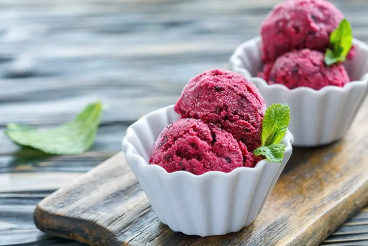 homemade ice cream of black currant in ceramic cup on a wooden stand, selective focus