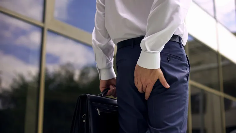 office worker feeling hemorrhoid pain while walking, sedentary lifestyle, health