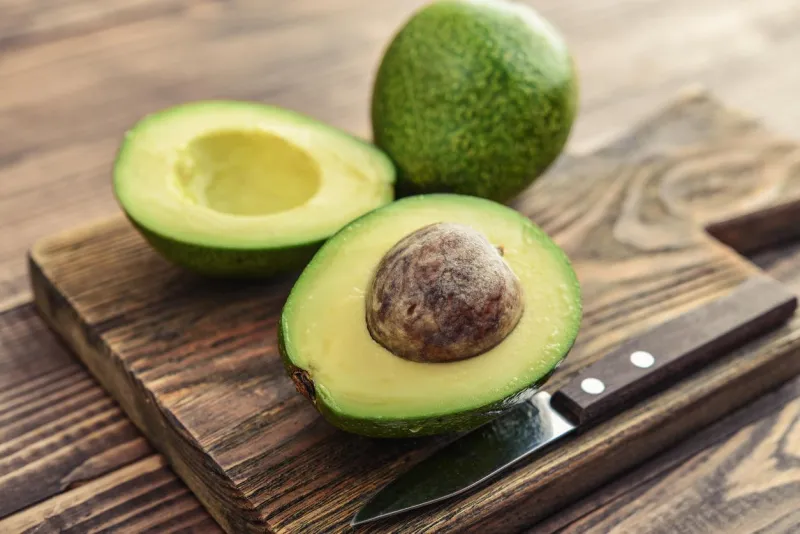 fresh avocado on cutting board over wooden background