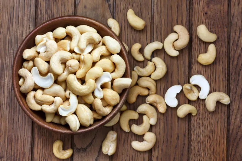 wooden bowl of cashew nuts from above on dark wood
