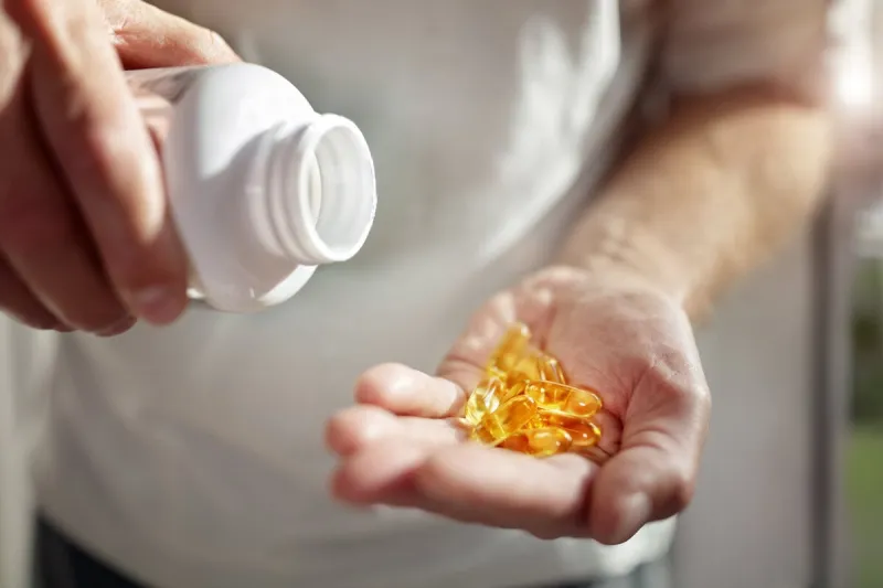 bottle of omega 3 fish oil capsules pouring into hand