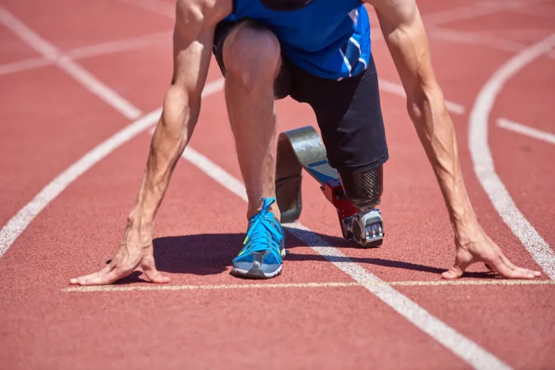 close up of adaptive sportsman with prosthetic foot training on running track at the stadium on sunny summer day real bodies, diversity, recovery, adaptive sportsman training concept
