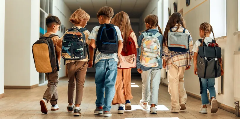 back to school a group of schoolchildren with backpacks walk along the school corridor during recess education and science concept