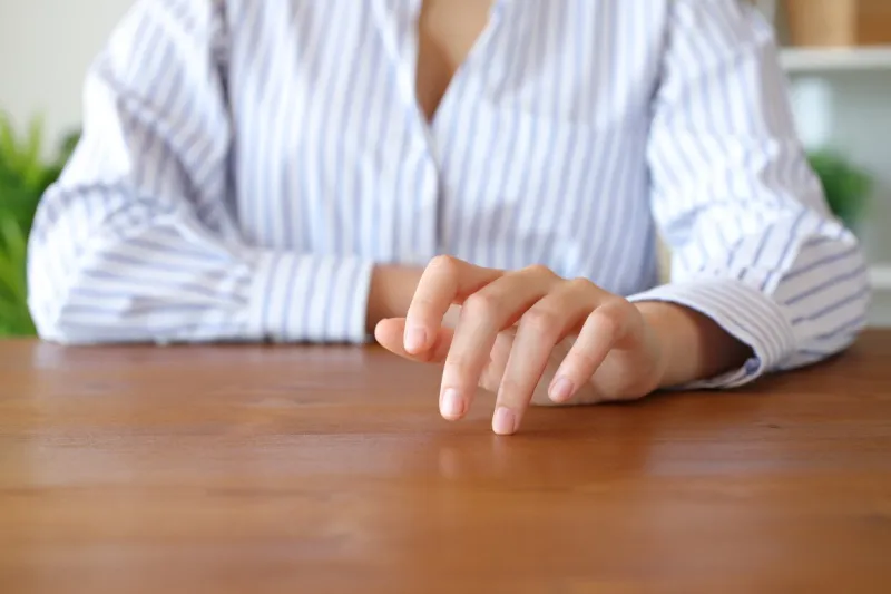 front view close up portrait of a woman hand waiting and tapping fingers on table at home